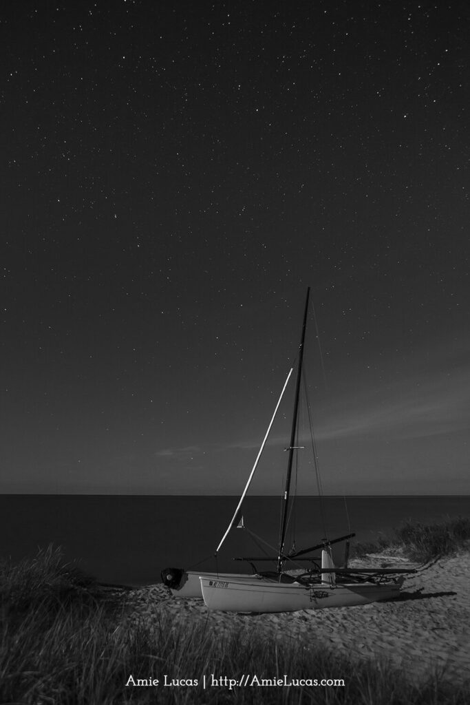 Black and white photograph with a sailboat under the night sky